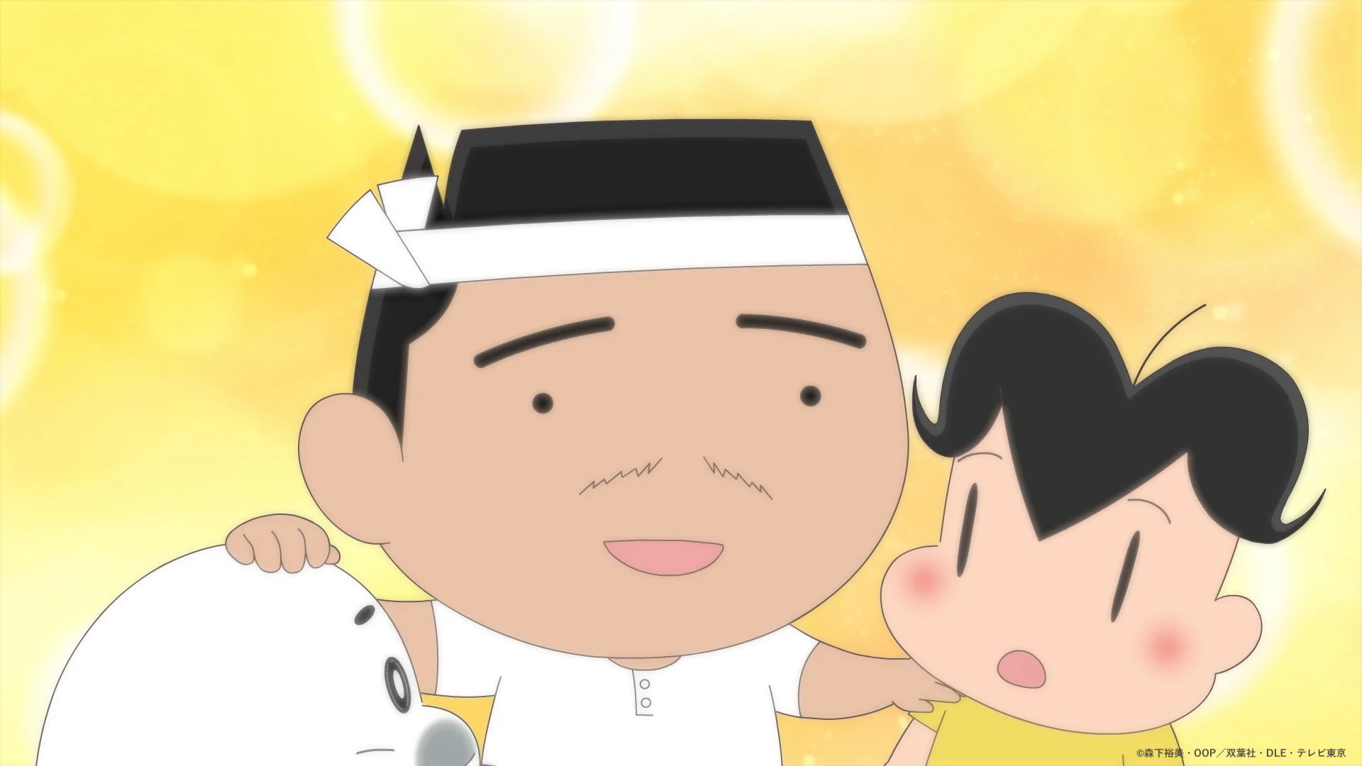 鉢巻を巻いた男性が少年と白い生き物を抱き寄せているアニメのワンシーン