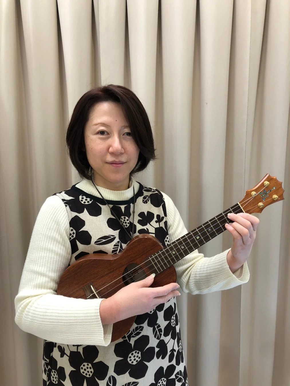 ウクレレを抱えてカメラを見つめる女性のポートレート。