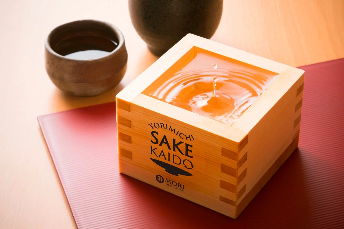 木製の枡に注がれた日本酒が波紋を広げ、その横には陶器のぐい呑みが置かれています。伝統的な和の雰囲気が漂う、美しいお酒の情景です。
