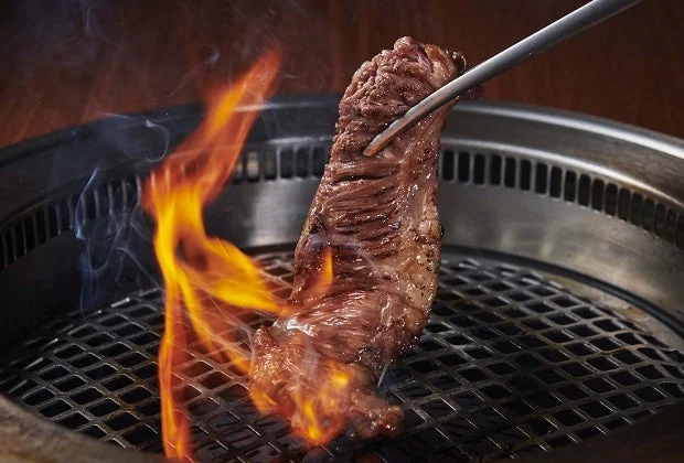 焼肉グリルで肉を掴むトング