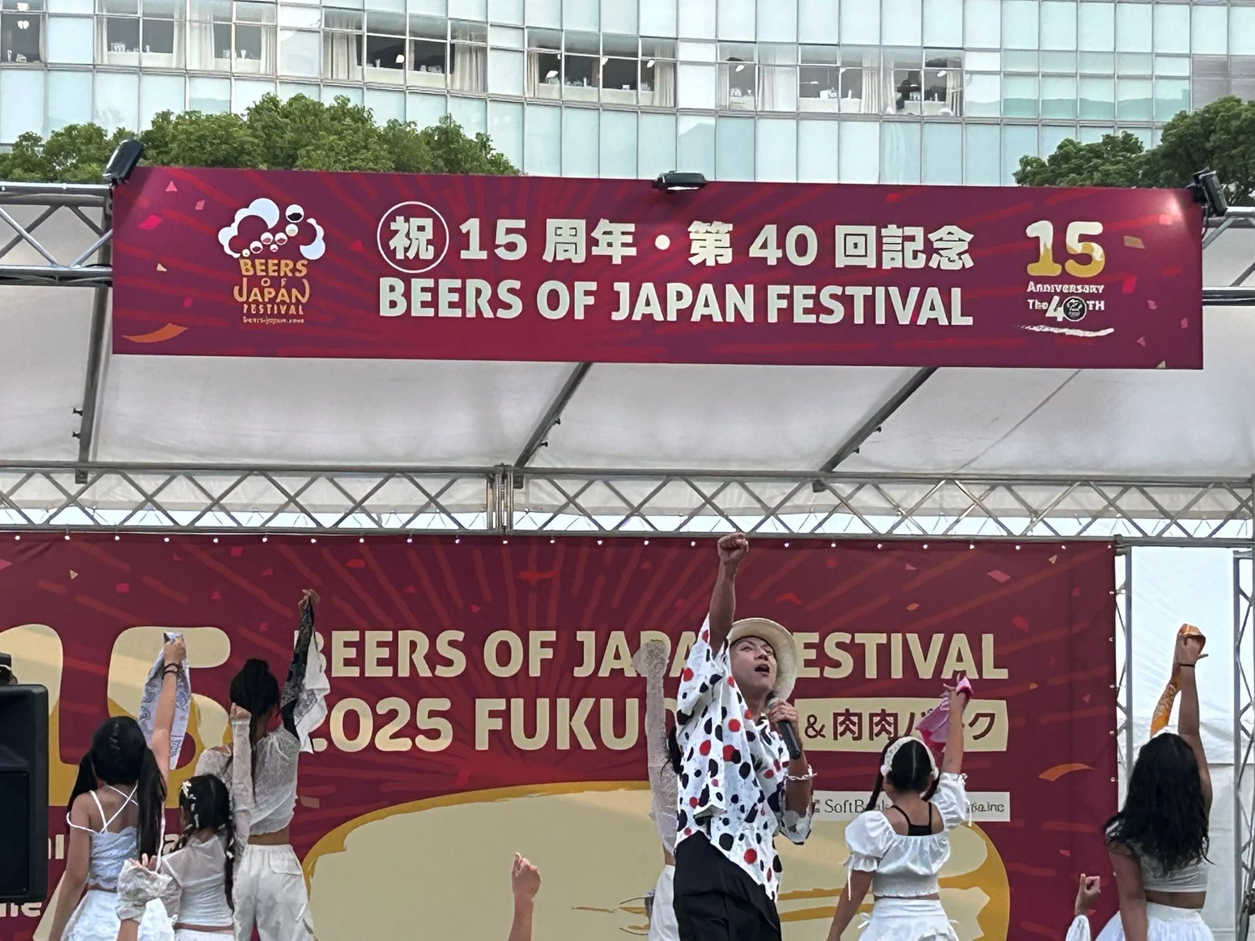 BEERS OF JAPAN FESTIVALの屋外ステージで、パフォーマーがマイクを持ち、観客を煽るように手を上げています。