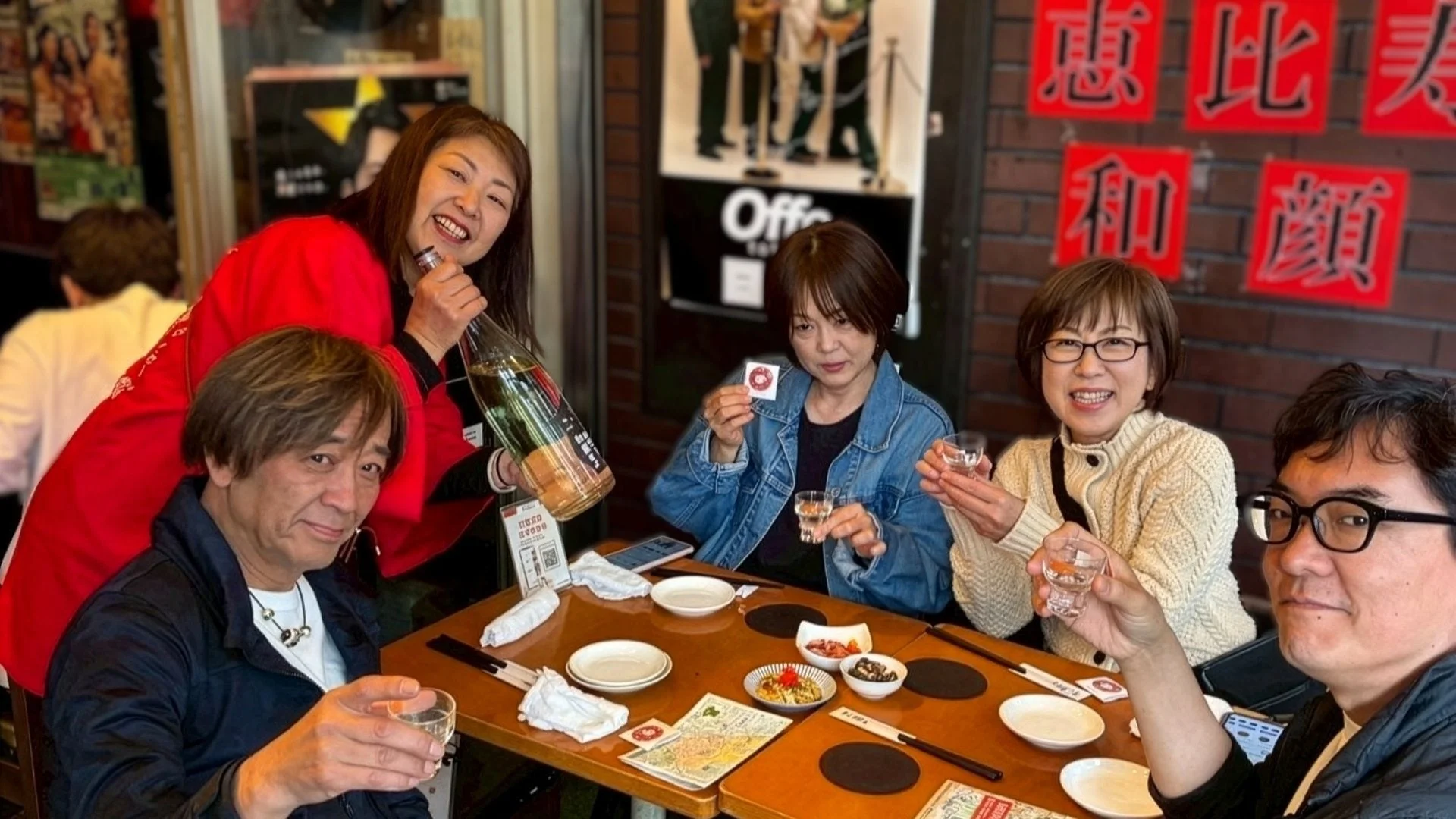 居酒屋で友人たちが集まり、日本酒を囲んで笑顔で乾杯している和やかな食事風景