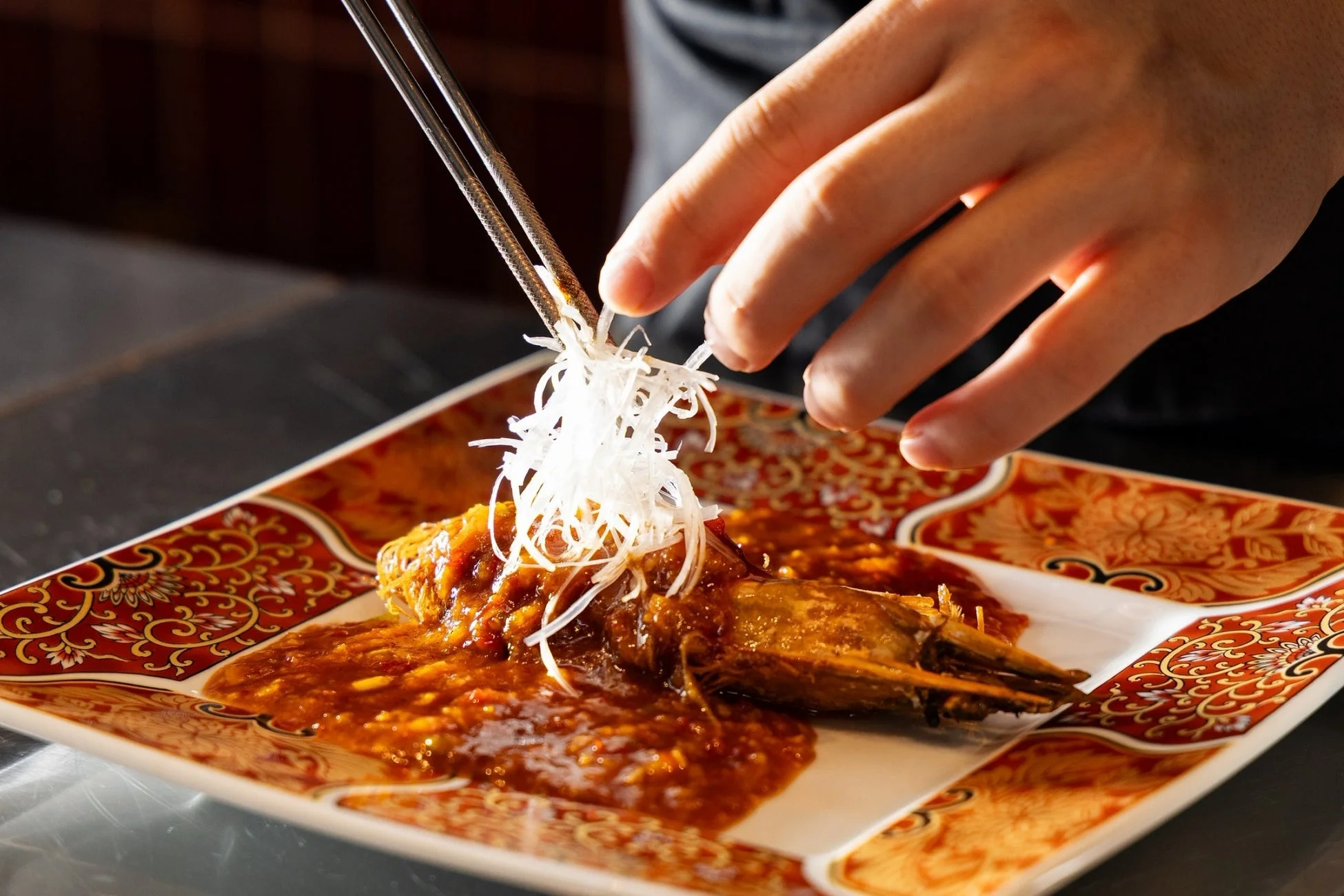 料理人がエビチリを盛り付ける様子