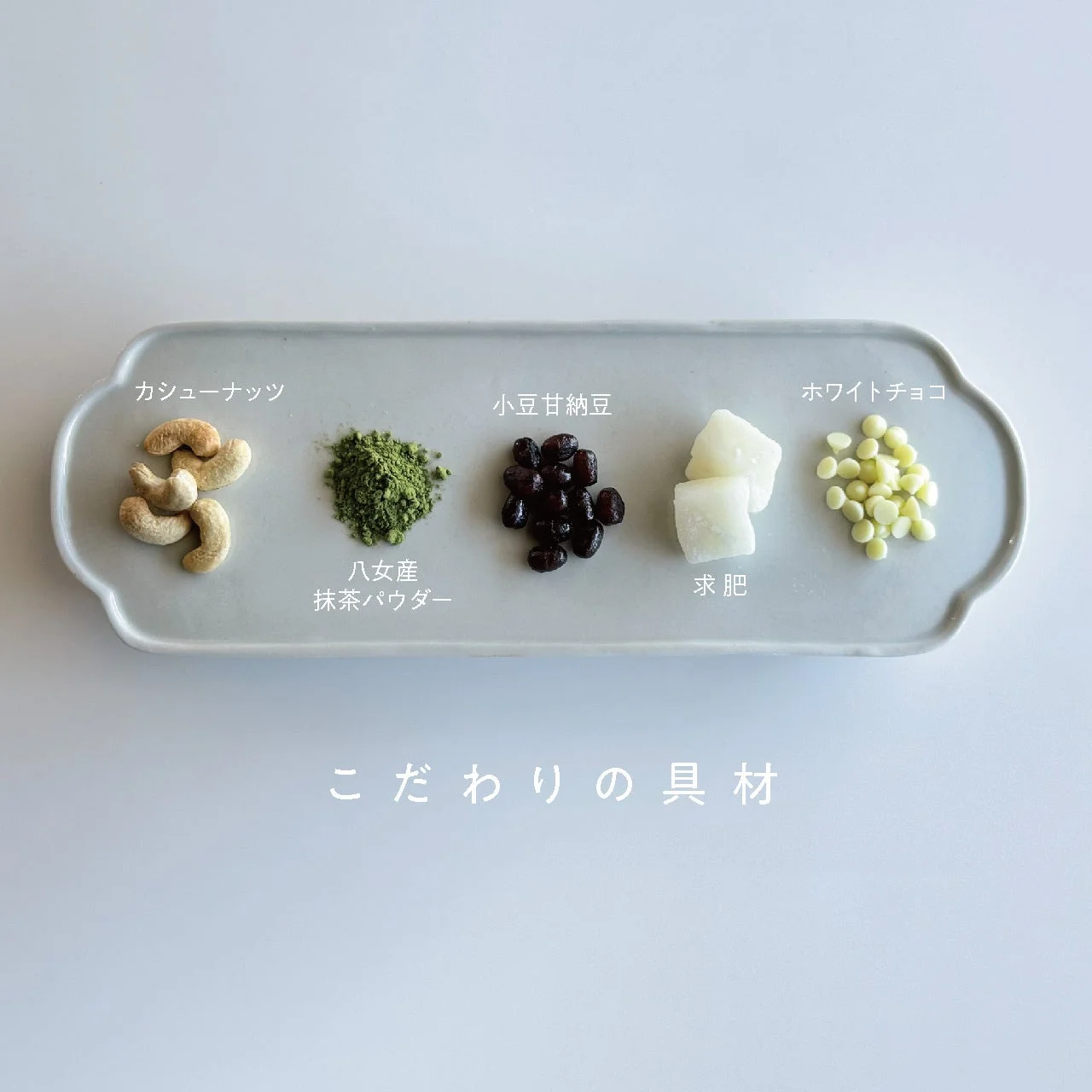 白地の皿にカシューナッツ、抹茶パウダー、小豆甘納豆、求肥、ホワイトチョコが並べられています